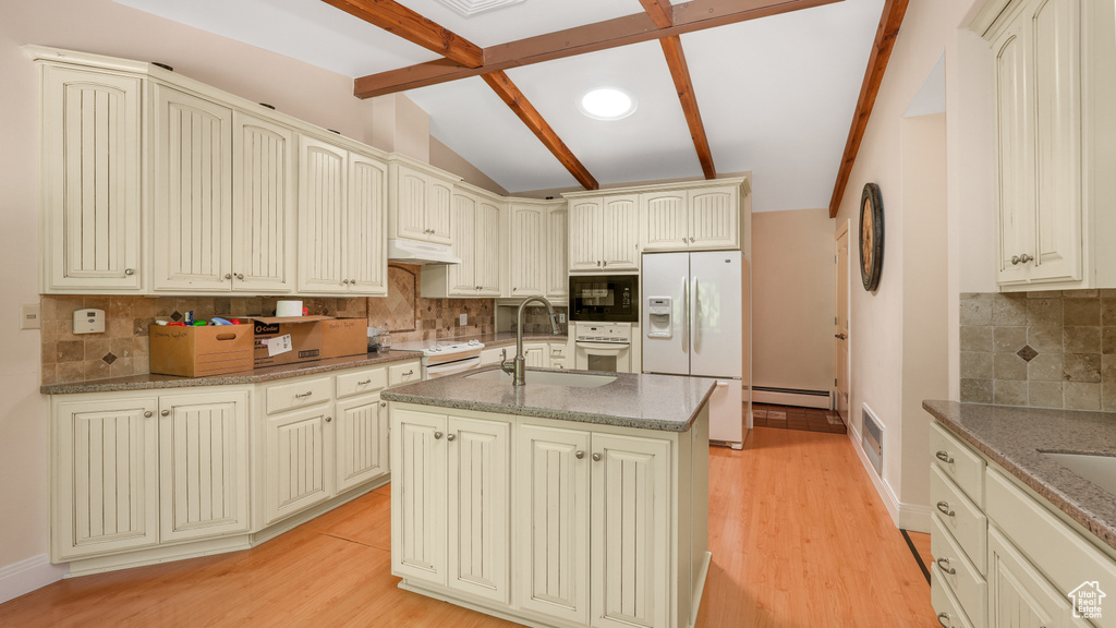 Kitchen featuring white appliances, cream cabinetry, a sink, tasteful backsplash, and stone countertops
