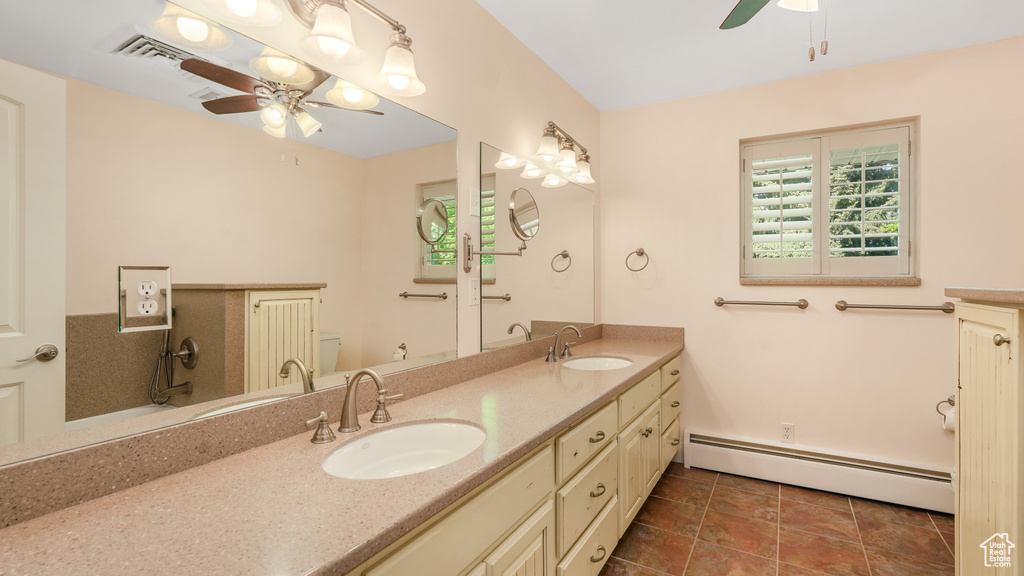 Full bath featuring ceiling fan, a baseboard heating unit, double vanity, and toilet