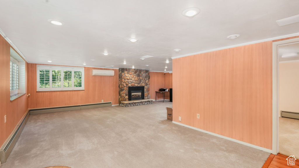 Unfurnished living room featuring an AC wall unit, baseboard heating, a fireplace, wooden walls, and carpet floors