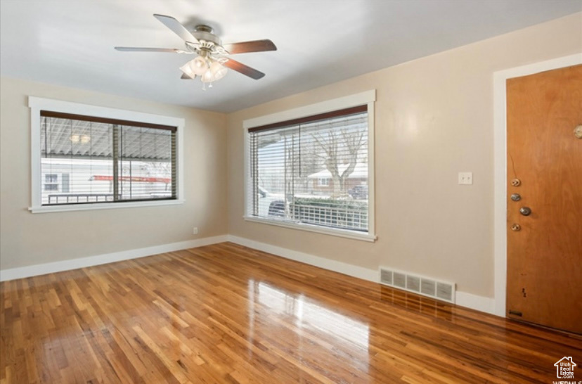 Unfurnished room with wood finished floors, a ceiling fan, and baseboards