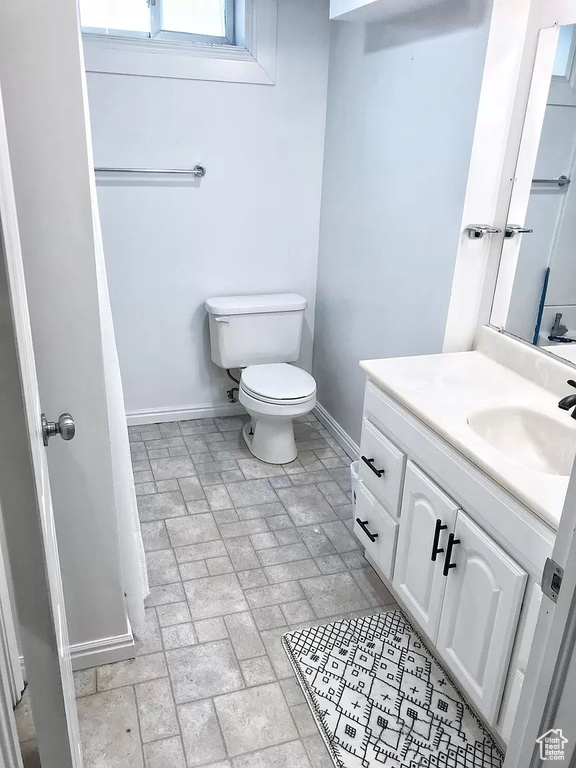 Full bath with baseboards, brick patterned floors, vanity, and toilet