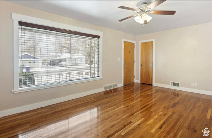Empty room with baseboards, wood finished floors, and a ceiling fan