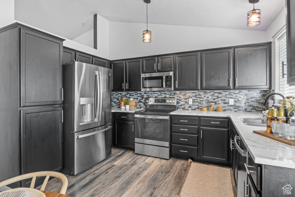 Kitchen with stainless steel appliances, vaulted ceiling, tasteful backsplash, and pendant lighting