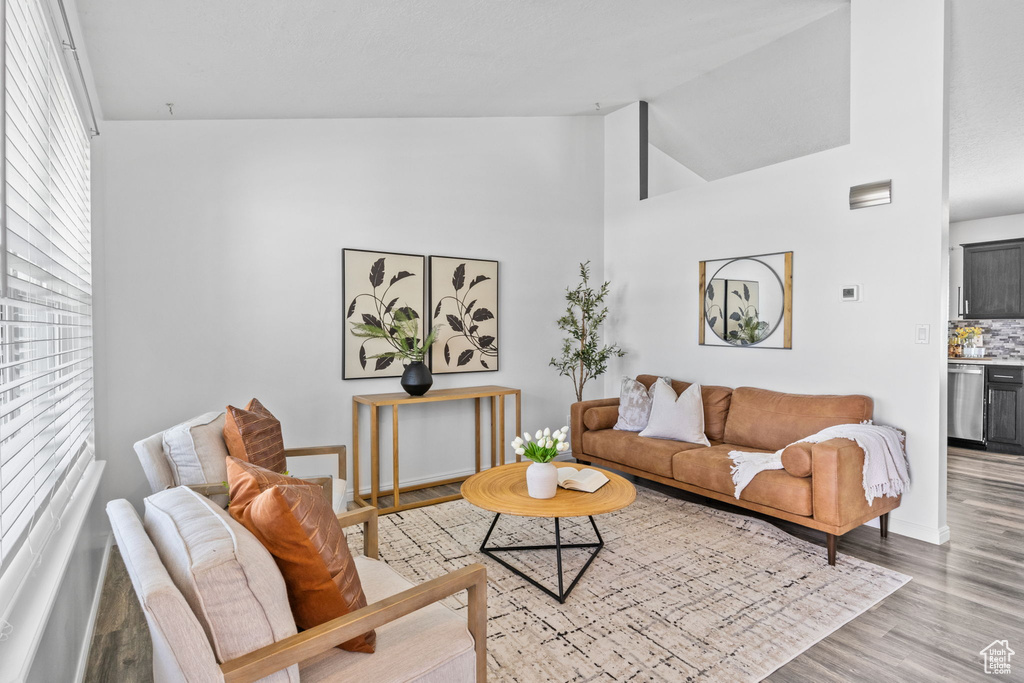 Living area with light wood finished floors, baseboards, and high vaulted ceiling