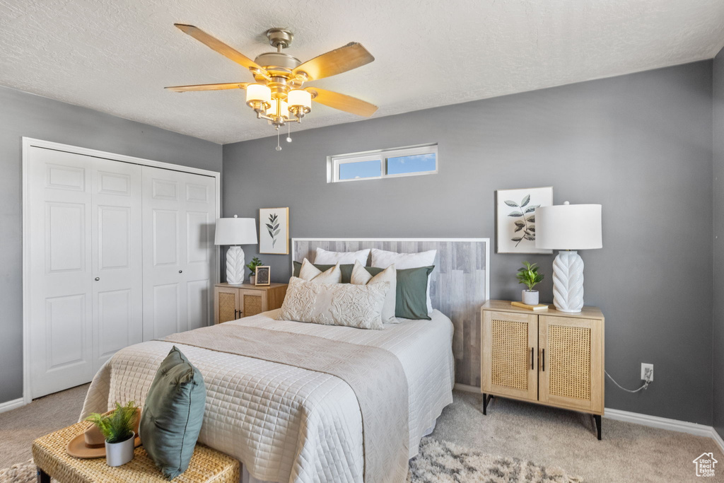 Bedroom featuring light colored carpet, a closet, baseboards, and a ceiling fan