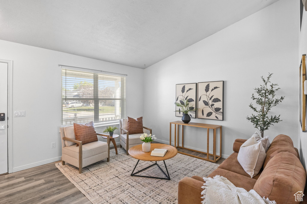 Living room featuring lofted ceiling, wood finished floors, and baseboards