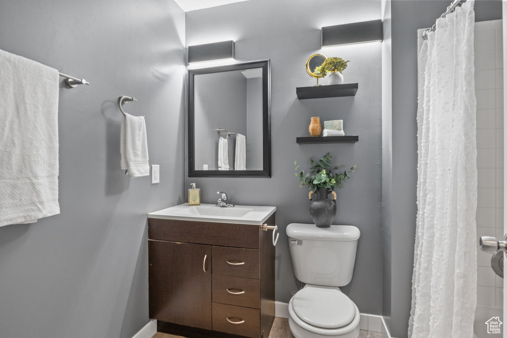 Bathroom with toilet, vanity, a shower with curtain, and baseboards