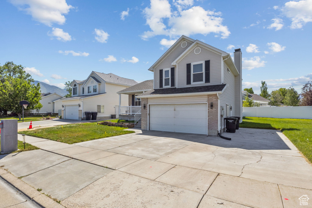 Traditional-style home with a chimney, brick siding, concrete driveway, and an attached garage