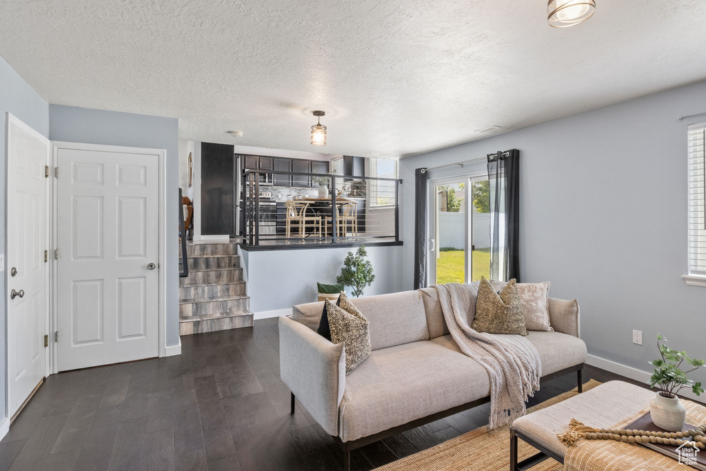 Living room with dark wood-style floors, baseboards, stairway, and a textured ceiling