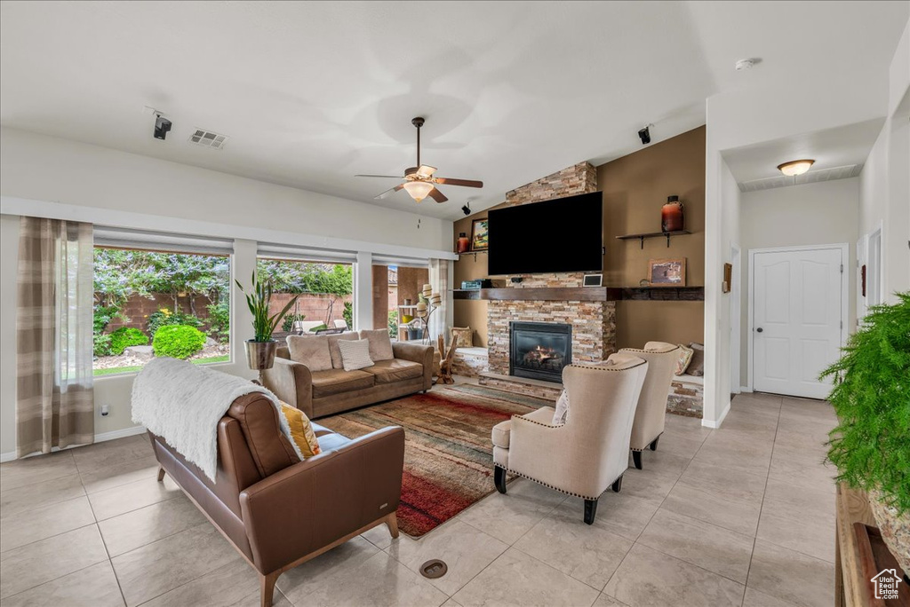 Living area with plenty of natural light, light tile patterned floors, ceiling fan, a fireplace, and lofted ceiling