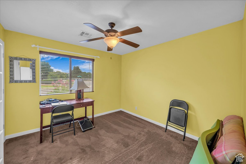 Carpeted home office featuring ceiling fan and baseboards