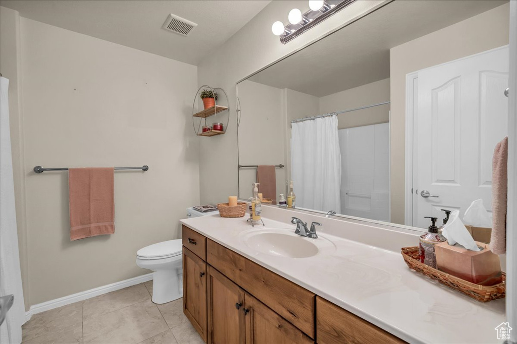 Full bathroom with baseboards, vanity, toilet, tile patterned floors, and a shower with curtain
