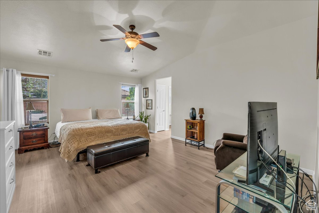 Bedroom featuring multiple windows, light wood-type flooring, baseboards, and lofted ceiling