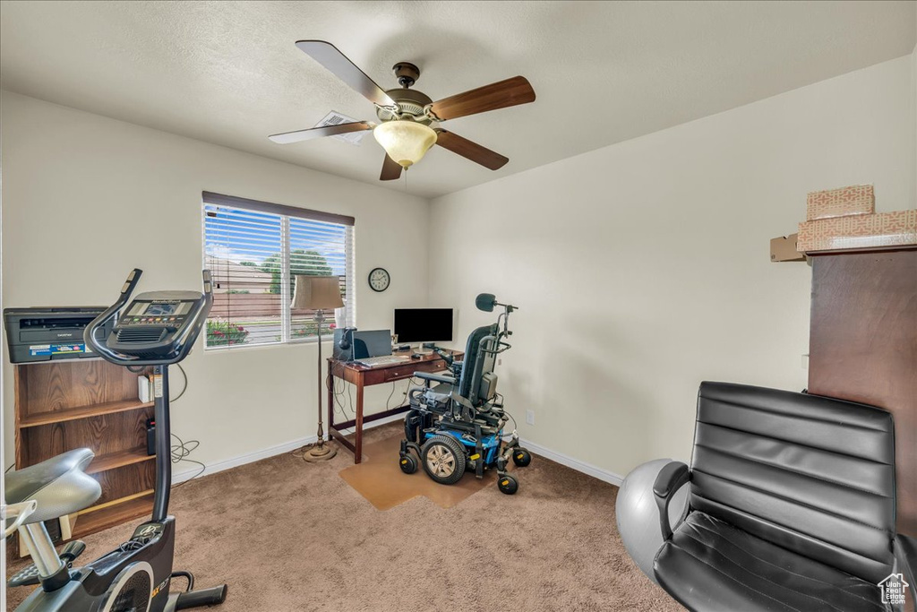 Carpeted office featuring a ceiling fan and baseboards
