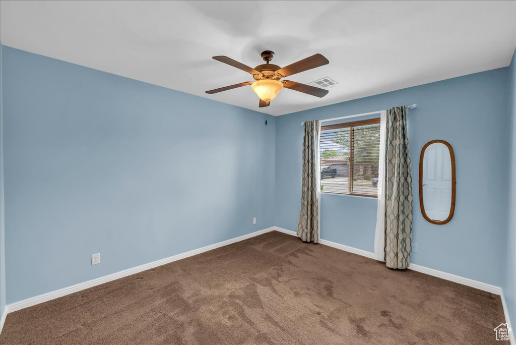 Carpeted spare room with ceiling fan and baseboards