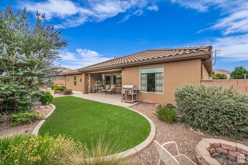 Rear view of property with stucco siding, a tile roof, and a patio