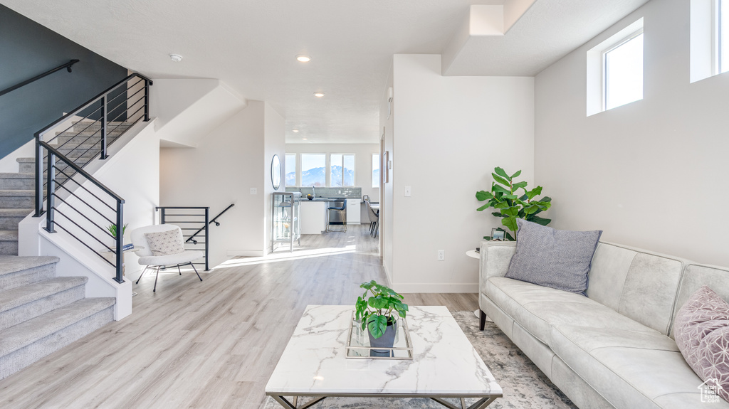 Living area with stairway, healthy amount of natural light, wood finished floors, and recessed lighting