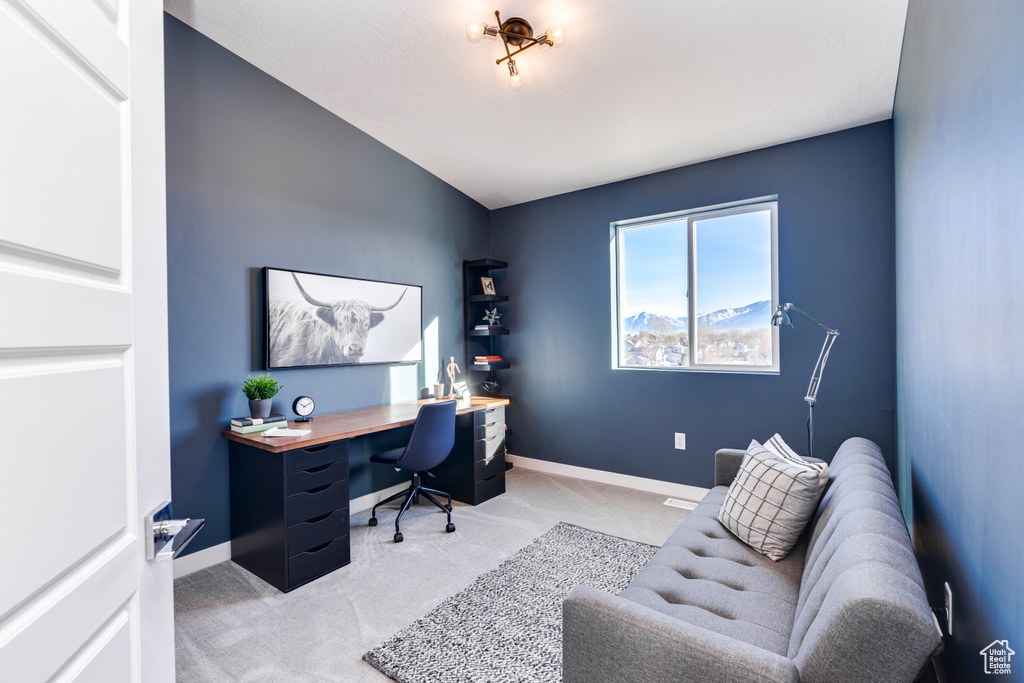 Office area featuring light carpet, baseboards, and vaulted ceiling