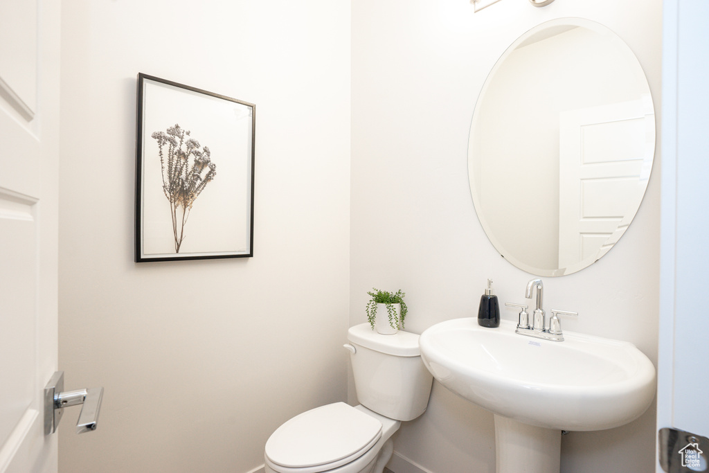 Bathroom featuring toilet, baseboards, and a sink
