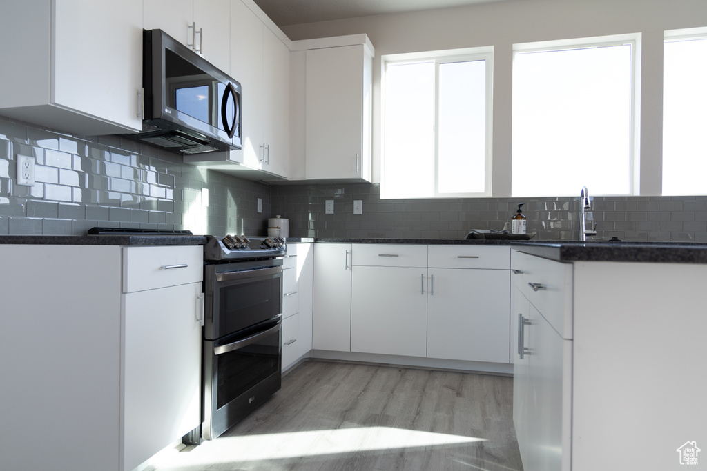Kitchen featuring double oven range, dark countertops, a sink, and decorative backsplash