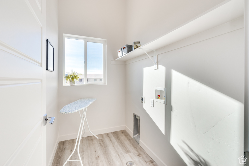 Laundry room featuring hookup for a washing machine, electric dryer hookup, light wood-style flooring, and baseboards