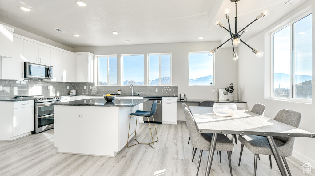 Kitchen featuring appliances with stainless steel finishes, a center island, light wood-style floors, tasteful backsplash, and recessed lighting