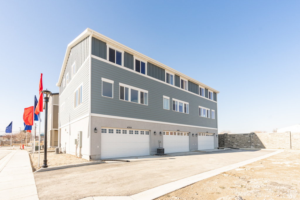 View of property featuring a garage, driveway, and central AC