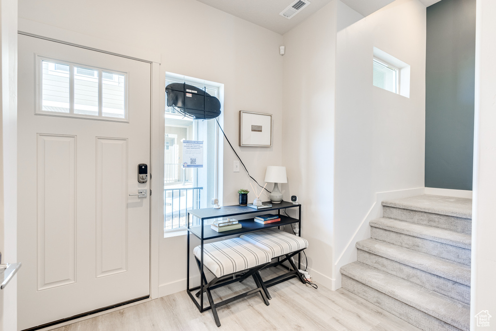 Foyer with light wood-style flooring, stairs, and baseboards