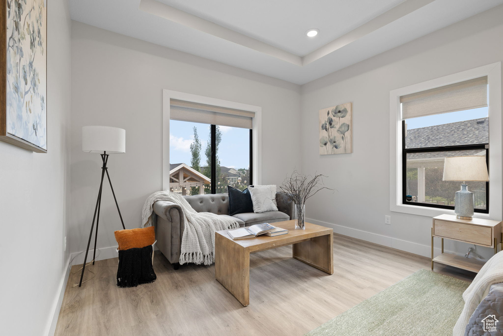 Living room featuring baseboards, light wood finished floors, recessed lighting, and a tray ceiling