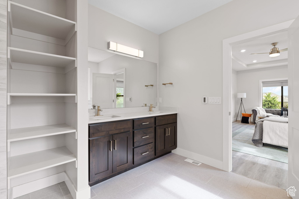 Ensuite bathroom featuring double vanity, baseboards, recessed lighting, and a ceiling fan