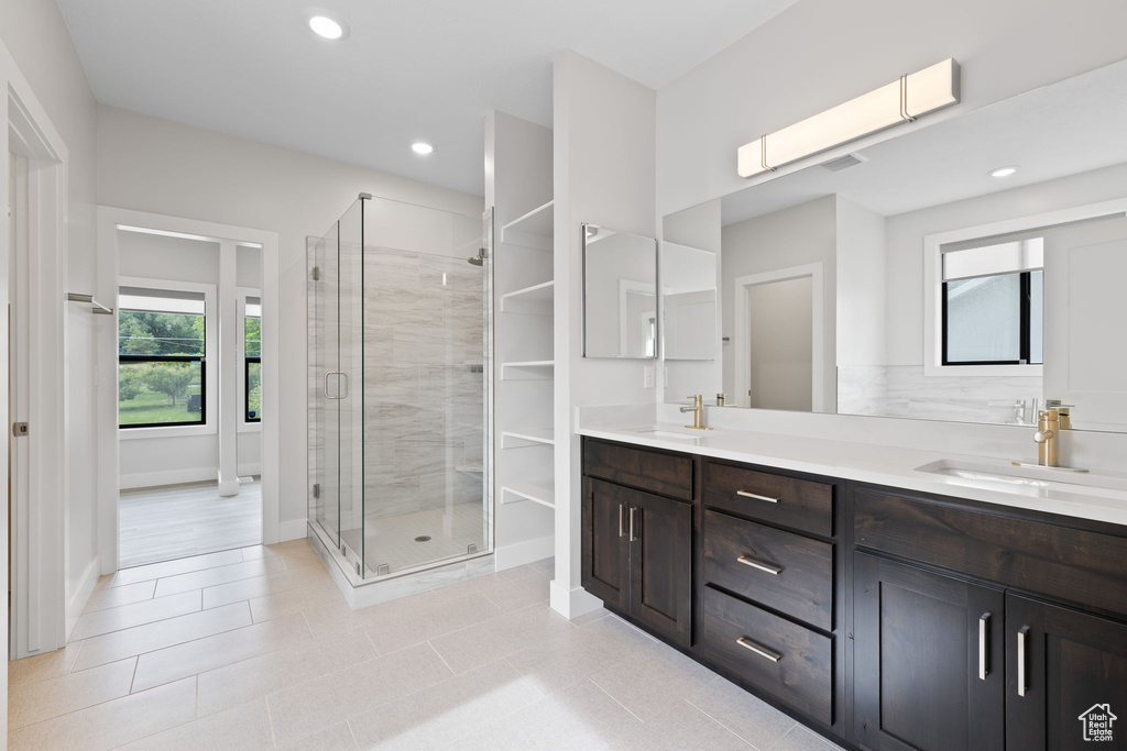 Bathroom with double vanity, a stall shower, baseboards, recessed lighting, and tile patterned flooring
