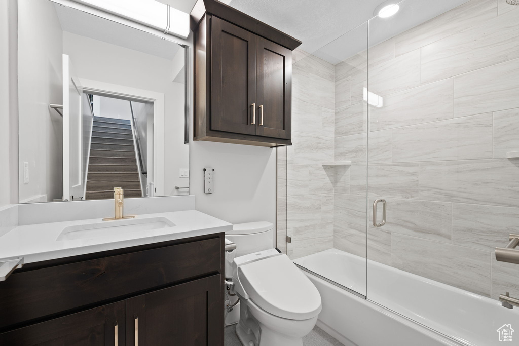 Full bath with toilet, vanity, and combined bath / shower with glass door