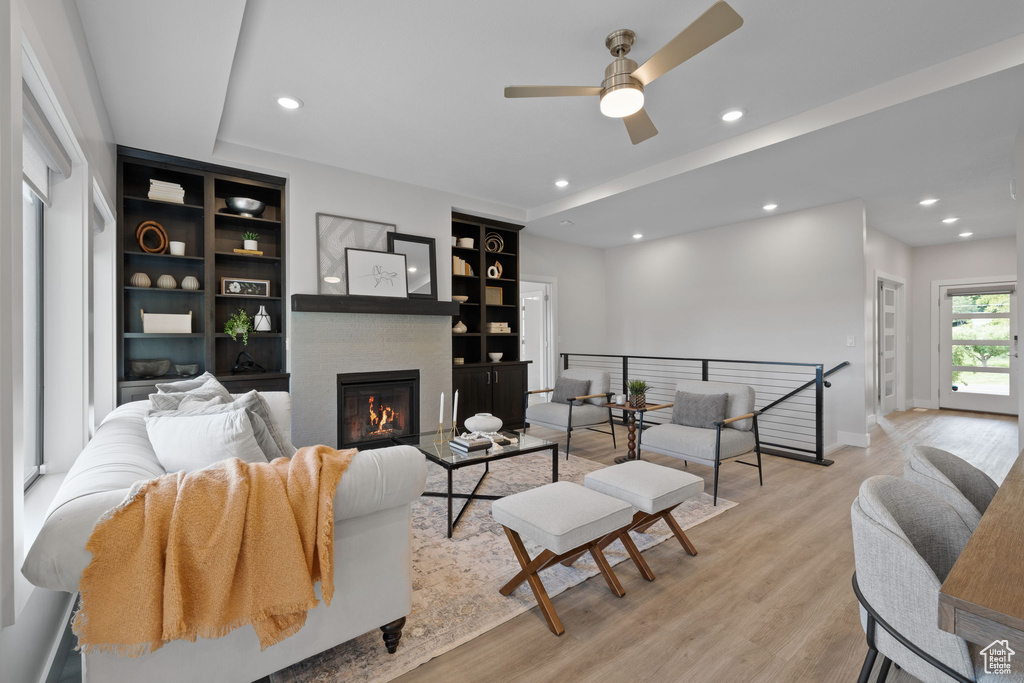 Living area with a ceiling fan, recessed lighting, light wood-type flooring, built in shelves, and baseboards