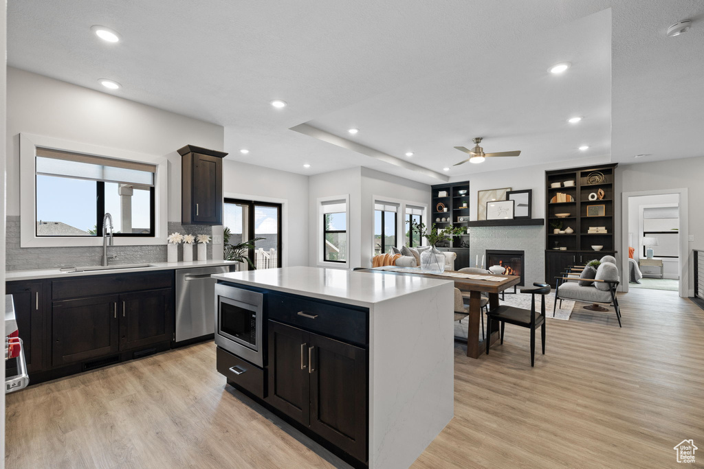 Kitchen with a sink, appliances with stainless steel finishes, light countertops, light wood-style flooring, and ceiling fan