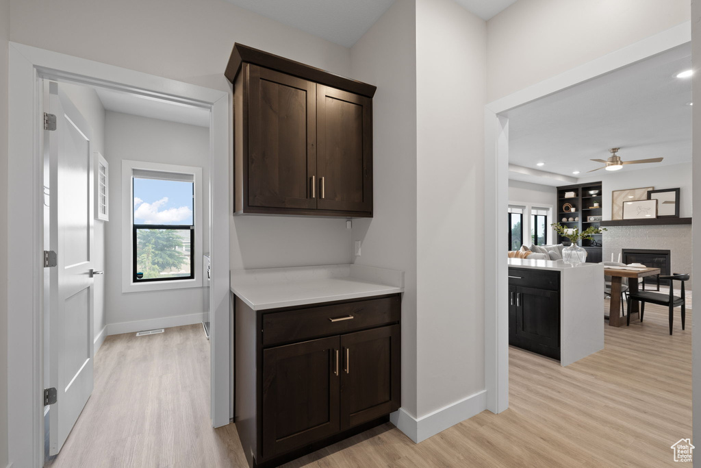Bar area featuring light wood-type flooring, baseboards, healthy amount of natural light, a glass covered fireplace, and recessed lighting