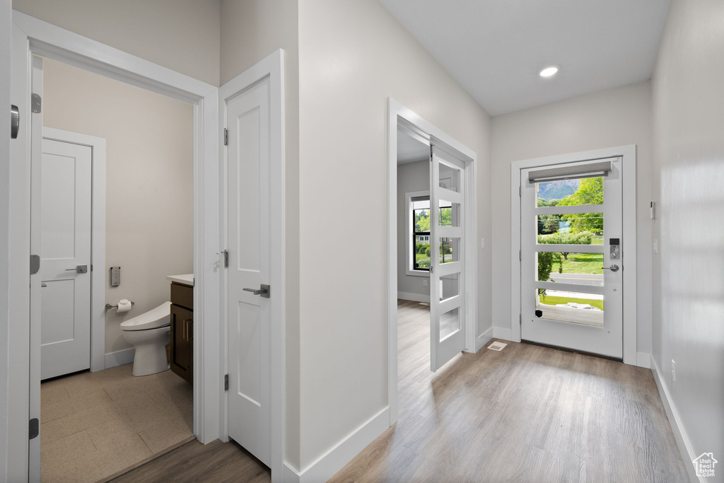 Doorway to outside featuring baseboards, light wood-type flooring, and recessed lighting