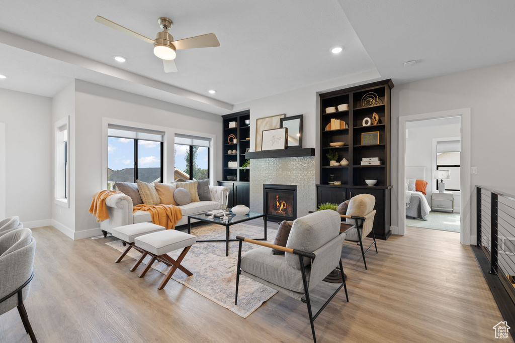 Living area with a glass covered fireplace, recessed lighting, ceiling fan, light wood-style flooring, and baseboards