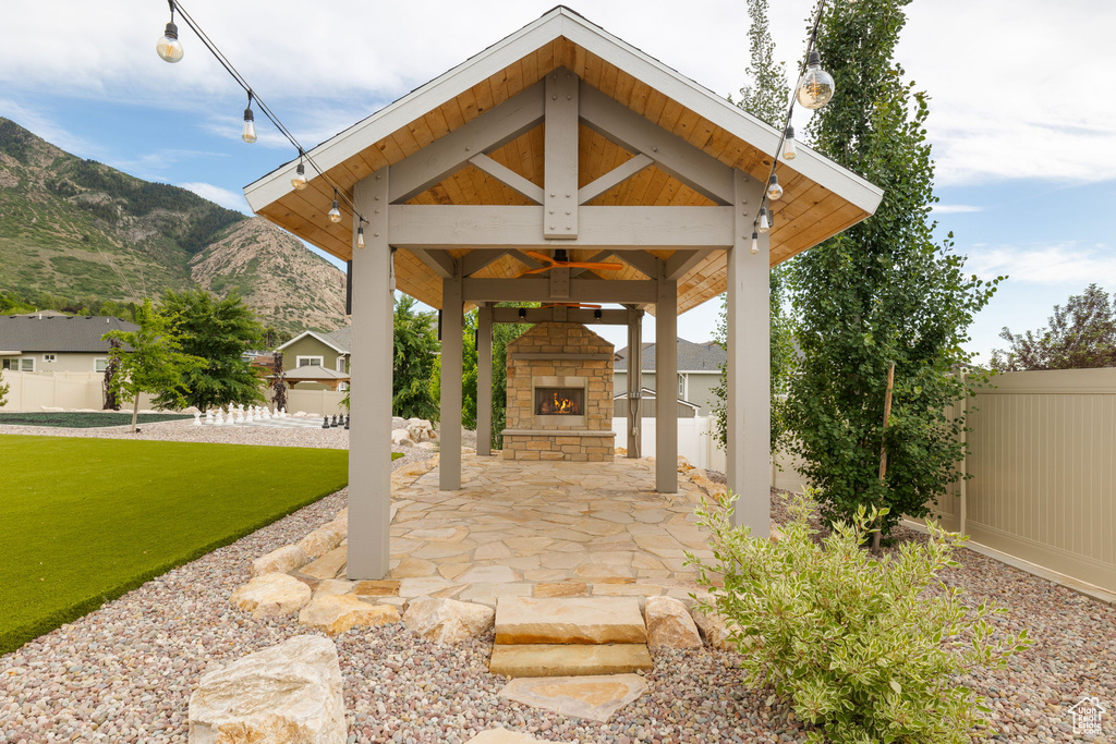 View of patio featuring an outdoor stone fireplace, a gazebo, and a mountain view