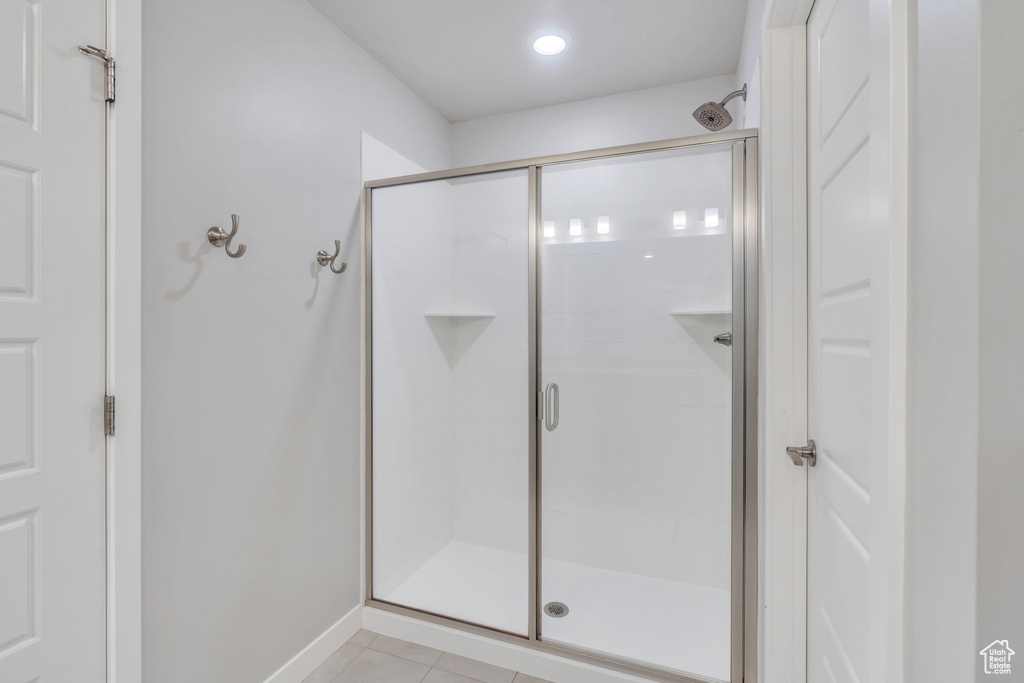 Full bathroom featuring a shower stall, tile patterned flooring, and baseboards
