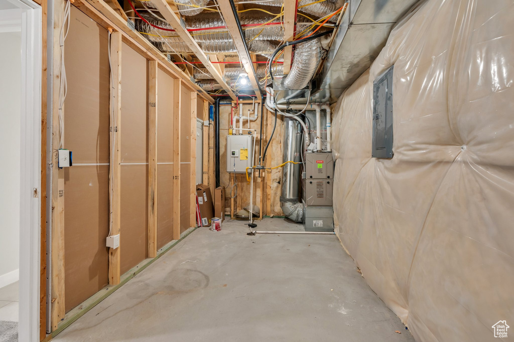 Unfinished below grade area featuring electric panel and heating unit