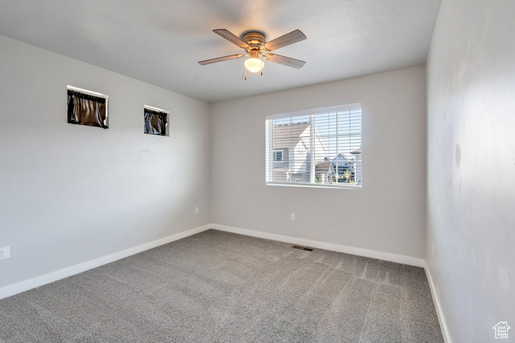 Carpeted spare room featuring baseboards and a ceiling fan