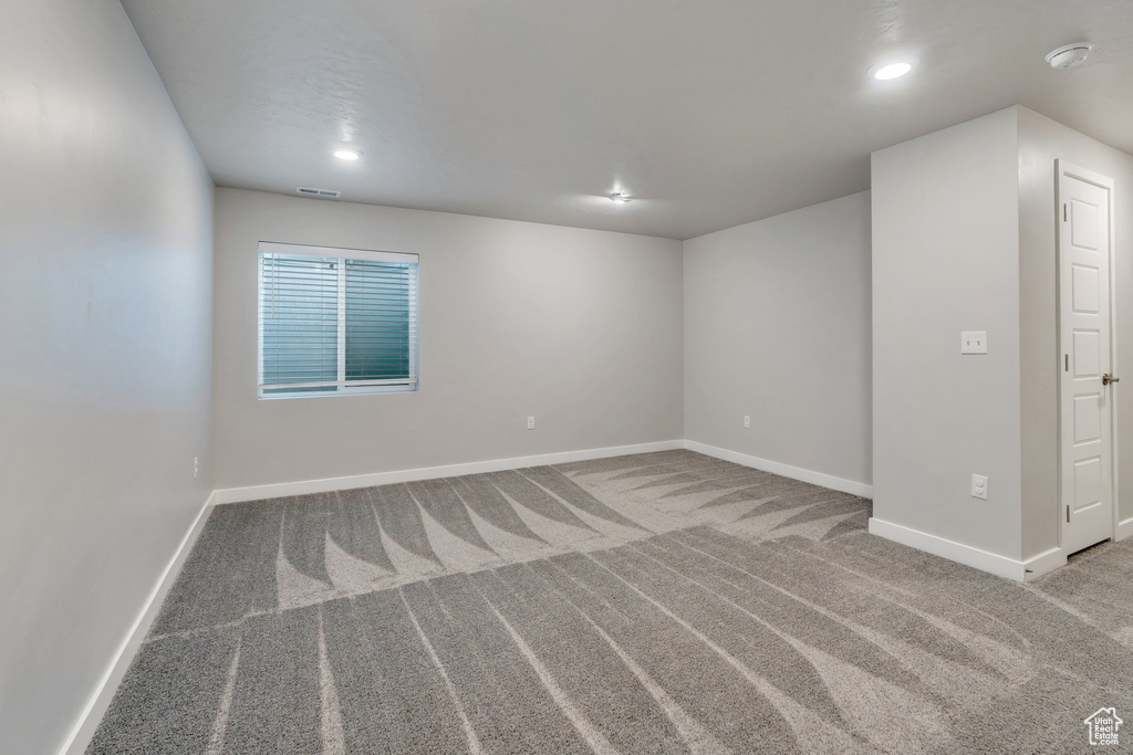 Carpeted spare room featuring baseboards, recessed lighting, and a smoke detector