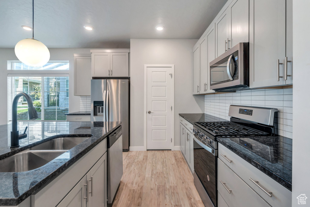 Kitchen featuring appliances with stainless steel finishes, a sink, tasteful backsplash, pendant lighting, and recessed lighting