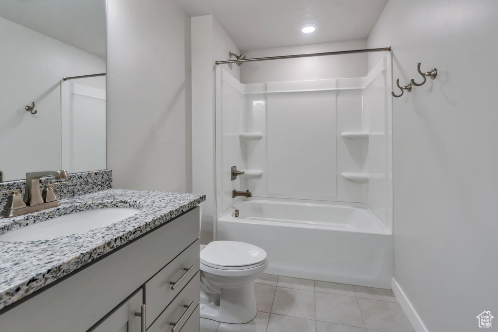 Full bath with tile patterned floors, vanity, bathing tub / shower combination, toilet, and baseboards