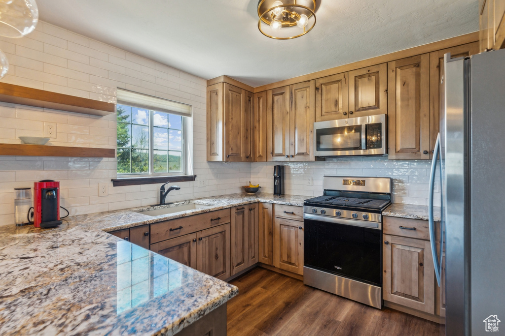 Kitchen featuring appliances with stainless steel finishes, a sink, open shelves, and decorative backsplash