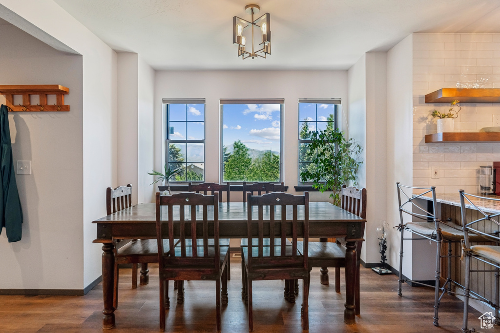 Dining room featuring dark wood-style floors, a chandelier, and baseboards