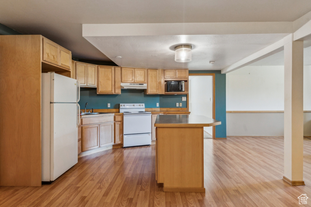 Kitchen featuring white appliances, under cabinet range hood, light wood finished floors, a sink, and light brown cabinetry