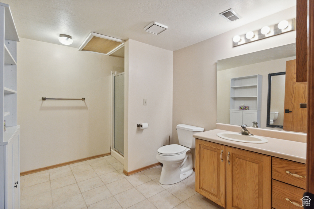 Full bath featuring toilet, vanity, a stall shower, baseboards, and tile patterned flooring