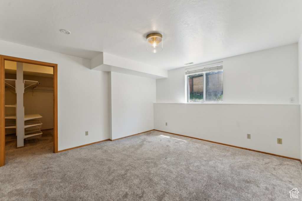 Unfurnished bedroom featuring carpet flooring, a walk in closet, baseboards, and a closet