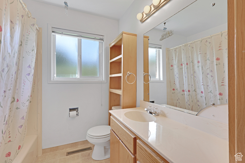 Bathroom with vanity, toilet, and shower / bath combo with shower curtain